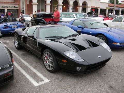 1998 Ford Crown Victoria - black Ford GT supercar with silver wheels and red brake calipers parked among other cars at a show.