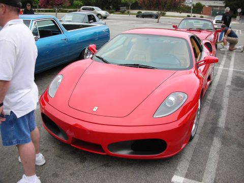 1998 Ford Crown Victoria - red Ferrari F430 coupe with tan interior parked at an outdoor car show as spectators look on.