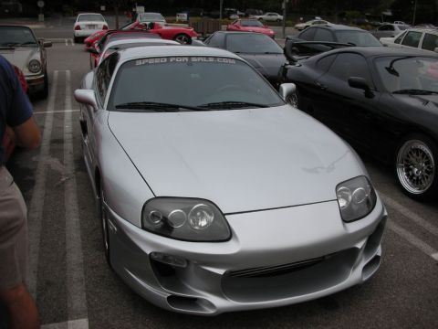 1998 Ford Crown Victoria - silver Toyota Supra with a front body kit and a SpeedForSale.com windshield banner parked at a meet.