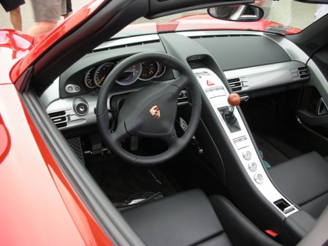 1998 Ford Crown Victoria - Interior of a red Porsche Carrera GT showing the Porsche steering wheel and the signature wood shift knob.