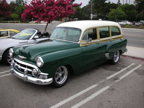 1998 Ford Crown Victoria - dark-green early-1950s Chevrolet station wagon with wood-trim sides and a white roof, parked at a show.