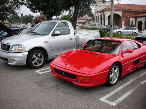 1998 Ford Crown Victoria - silver Ford F-150 Lightning sport truck parked next to a red Ferrari F355 coupe in a strip-mall lot.