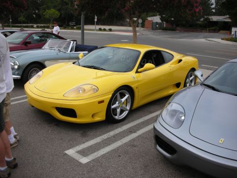 1998 Ford Crown Victoria - yellow Ferrari 360 Modena coupe parked between a vintage roadster and a silver Ferrari, with bystanders nearby.