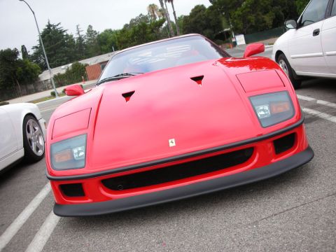 1998 Ford Crown Victoria - Front three-quarter view of a red Ferrari F40 showing its hood vents, black splitter and Ferrari badge, parked on a street.