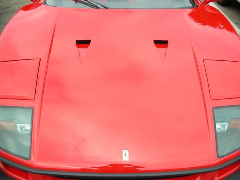 1998 Ford Crown Victoria - Tight close-up of a red Ferrari's hood and nose, showing twin air vents and the prancing-horse badge above the grille.