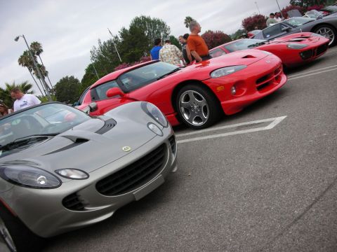 1998 Ford Crown Victoria - silver Lotus Elise sits in the foreground with a red Dodge Viper roadster and other sports cars lined up behind at a car meet.