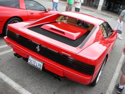1998 Ford Crown Victoria - rear of a red Ferrari Testarossa shows its slatted engine cover, badge, and quad exhaust tips with a California plate at a car meet.