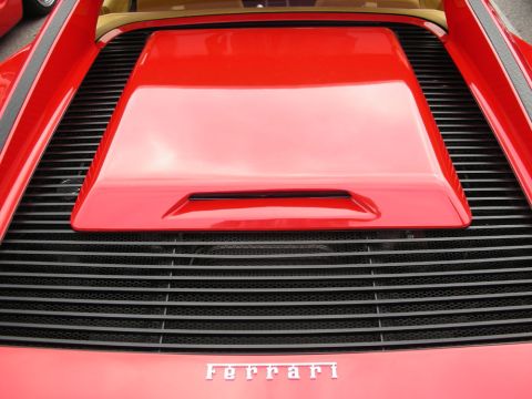 1998 Ford Crown Victoria - close-up of a red Ferrari's slatted rear engine cover with the Ferrari name spelled out in chrome script across the bottom.