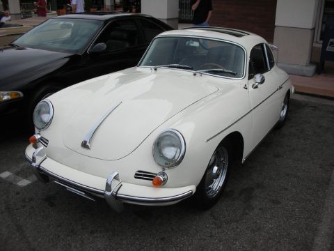 1998 Ford Crown Victoria - cream-colored classic Porsche 356 coupe with chrome bumpers and round headlights sits parked beside a black car on a street.