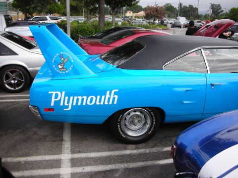 1998 Ford Crown Victoria - light blue Plymouth Superbird shows off its towering rear wing and black vinyl roof in a packed car-show lot.