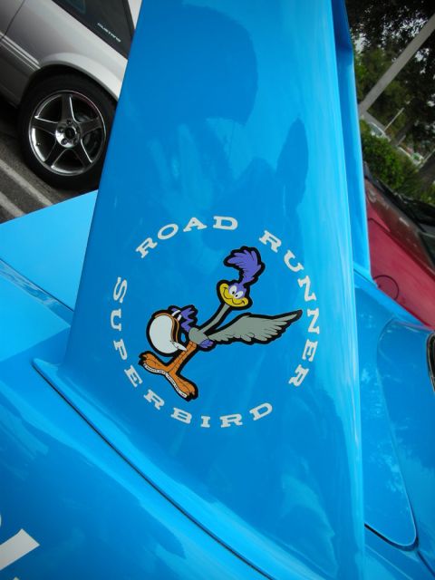 1998 Ford Crown Victoria - Road Runner Superbird cartoon decal sits in a white ring on the glossy blue surface of a car's rear wing.