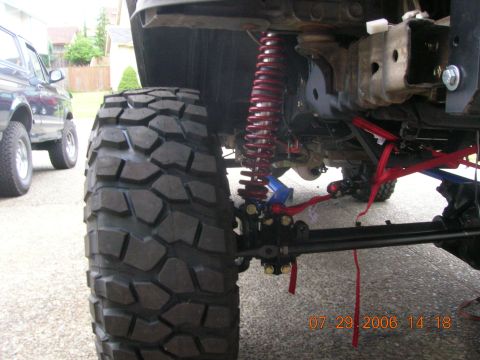 1996 Ford Bronco - A vehicle's suspension system and oversized tire are shown, with another vehicle visible in the background.
