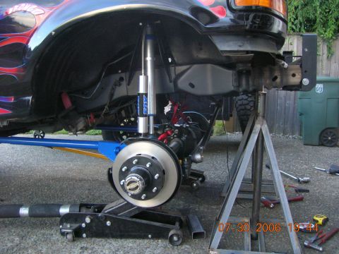 1996 Ford Bronco - The vehicle's front end is raised on jack stands, showing custom suspension components and a hydraulic jack.
