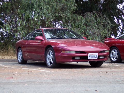 1995 Ford Probe - A red 1995 Ford Probe is parked in a lot, with another red vehicle partially visible to the right.