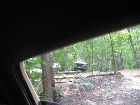 1995 Ford C-350 (Centurion Conversions) - A white truck is parked on a dirt path surrounded by trees and fallen logs.