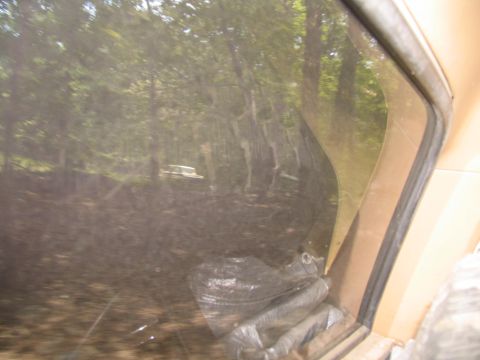 1995 Ford C-350 (Centurion Conversions) - A white van is visible in a wooded area, seen through the window of another vehicle.