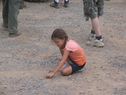 1995 Ford C-350 (Centurion Conversions) - A young girl with braided hair plays on a gravel surface, with adults standing in the background.