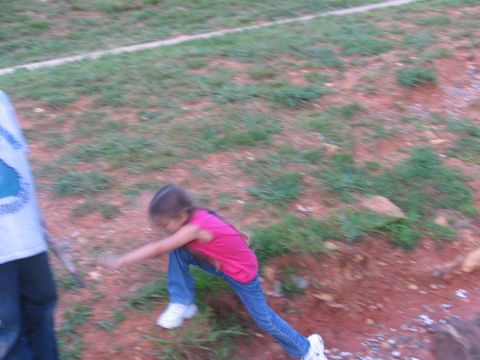1995 Ford C-350 (Centurion Conversions) - A young girl in a pink shirt and blue jeans is captured in motion on a grassy, reddish-brown terrain.