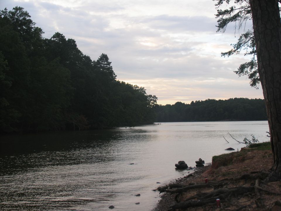 Lake with tree-lined shore under cloudy sky