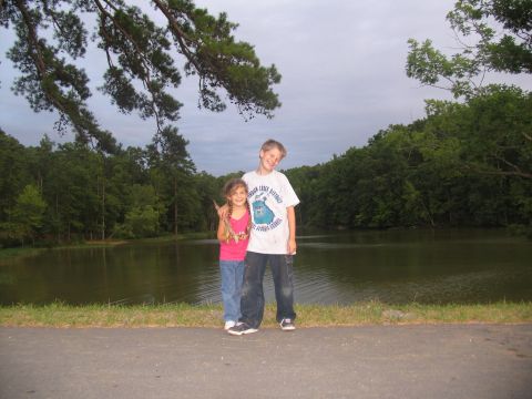 1995 Ford C-350 (Centurion Conversions) - Two children pose for a photo by a calm lake surrounded by dense green trees.