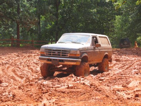 1995 Ford C-350 (Centurion Conversions) - Muddy 1995 Ford Bronco navigating a challenging off-road trail.