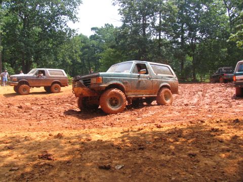1995 Ford C-350 (Centurion Conversions) - Multiple off-road vehicles navigate a muddy track during an event.