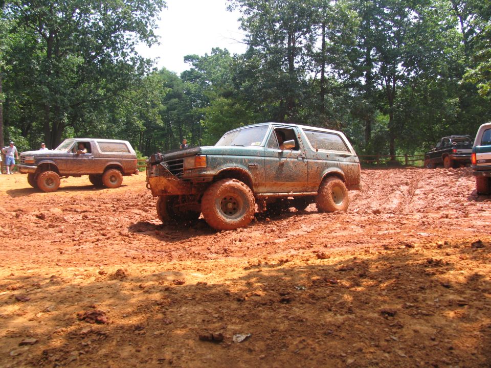 Muddy Ford Bronco and other off-road vehicles on a dirt track