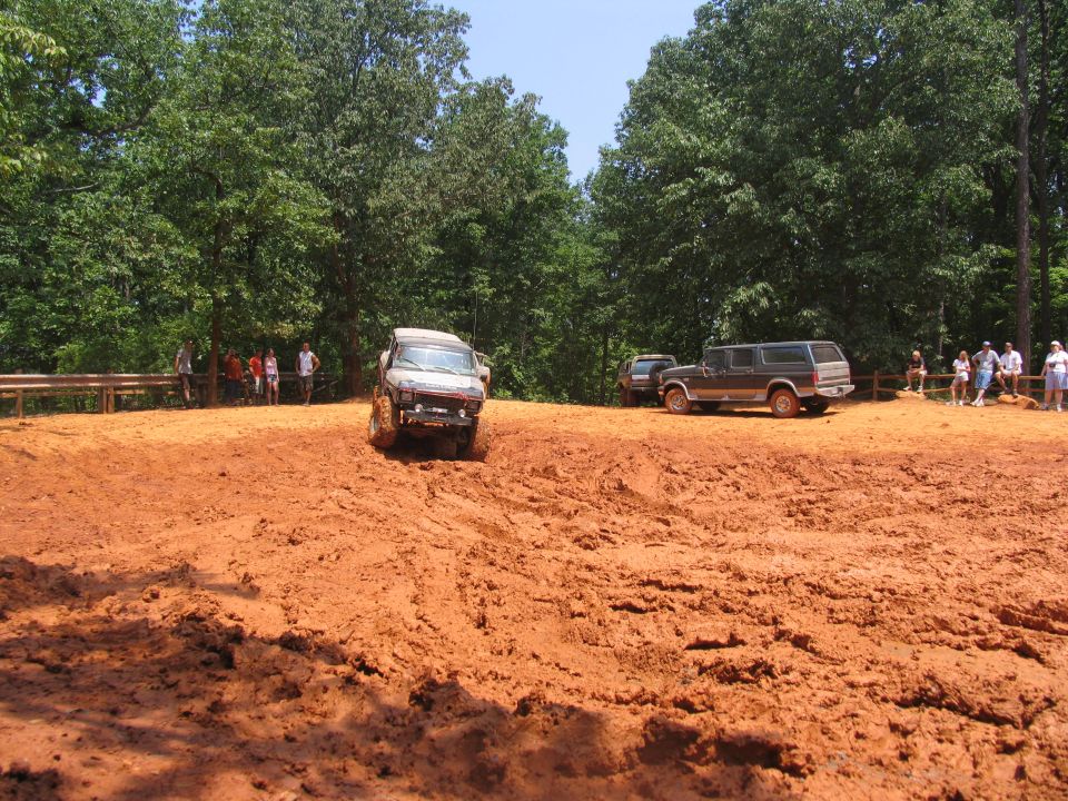 1995 Ford C-350 (Centurion Conversions) driving on a muddy off-road course with another SUV parked nearby