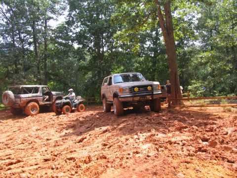 1995 Ford C-350 (Centurion Conversions) - Off-road vehicles navigate a challenging muddy terrain during an event.