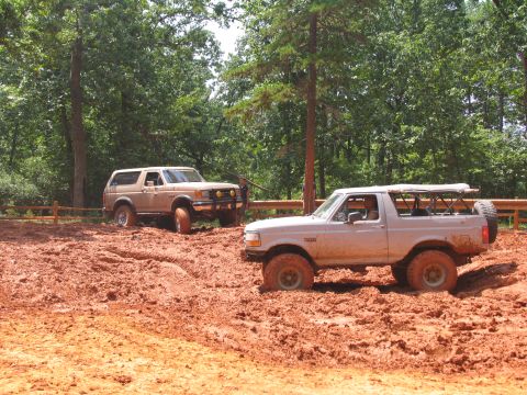 1995 Ford C-350 (Centurion Conversions) - Two Ford Broncos navigate a challenging muddy terrain during an off-road event.