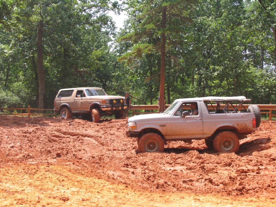 Two Ford Broncos stuck in deep mud, one in front and one behind