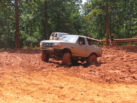1995 Ford C-350 (Centurion Conversions) - A lifted Ford Bronco navigates a muddy off-road course, with another vehicle visible in the background.