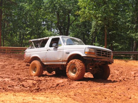 1995 Ford C-350 (Centurion Conversions) - White 1995 Ford Bronco navigating a muddy off-road trail.