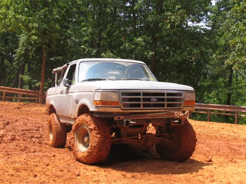1995 Ford C-350 (Centurion Conversions) - A lifted Ford Bronco with mud-caked tires sits in a muddy off-road area.
