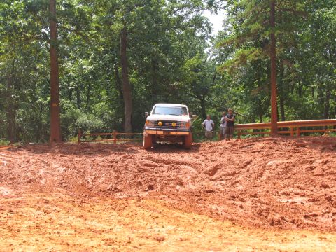 1995 Ford C-350 (Centurion Conversions) - A white Ford F-Series truck navigates a muddy terrain with onlookers observing.