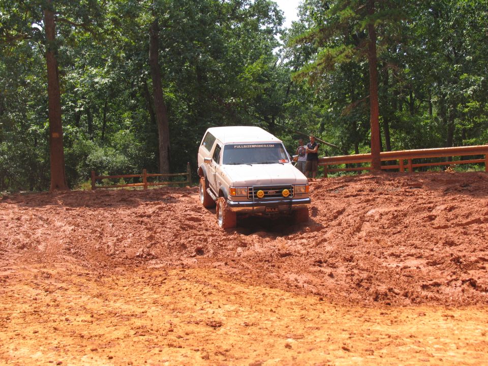 White SUV with off-road tires driving through mud; "FULLSIZEBRONCO.COM" sticker on windshield