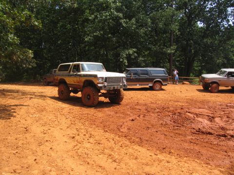 1995 Ford C-350 (Centurion Conversions) - A heavily modified Ford Bronco with oversized tires navigates a muddy off-road course alongside other vehicles.