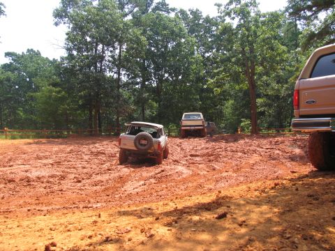 1995 Ford C-350 (Centurion Conversions) - Multiple vehicles are stuck in deep mud during an off-road event.