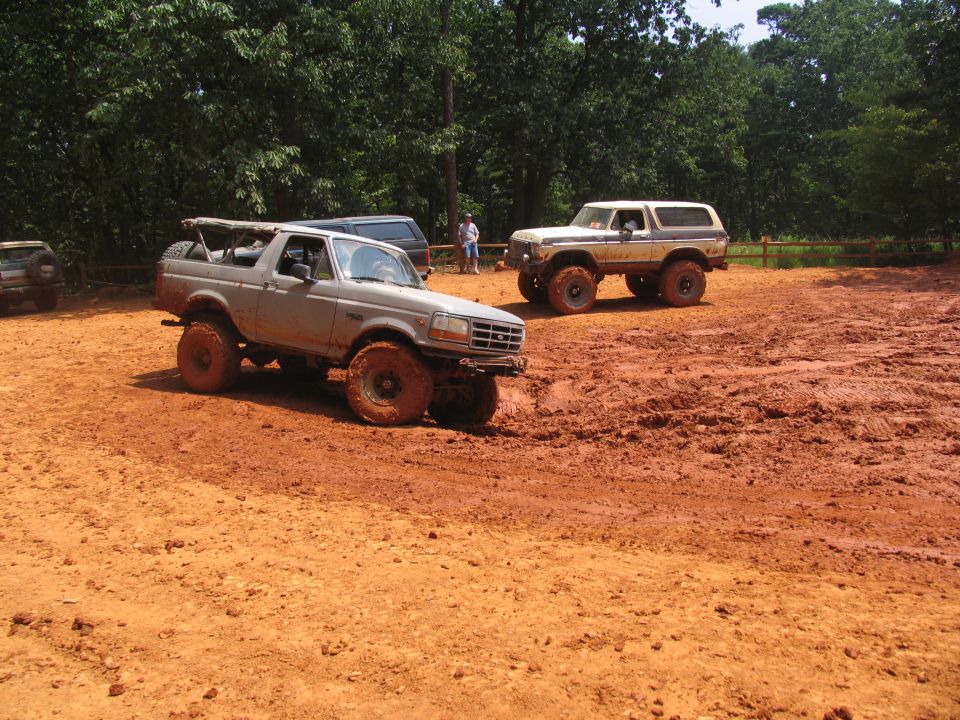 Gray Ford Bronco with lifted suspension and off-road tires driving through mud