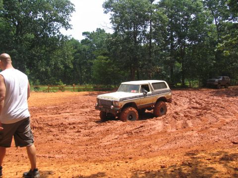 1995 Ford C-350 (Centurion Conversions) - A tan and white Ford Bronco navigates through thick mud during an off-road event, with another vehicle visible in the background.