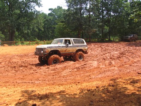 1995 Ford C-350 (Centurion Conversions) - A lifted Ford Bronco navigates a muddy off-road course, with another vehicle visible in the distance.