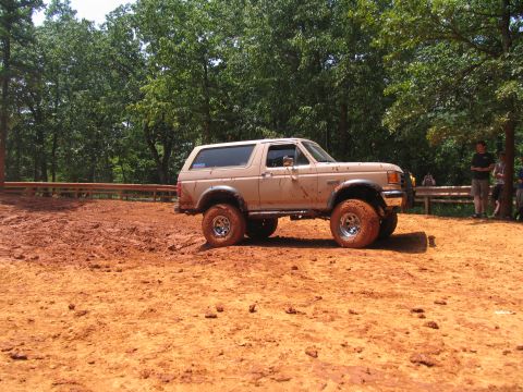 1995 Ford C-350 (Centurion Conversions) - A tan Ford Bronco with off-road tires navigates a muddy track during an event in July 2006.