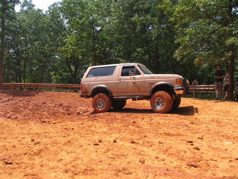 Tan Ford Bronco with lifted suspension on muddy terrain