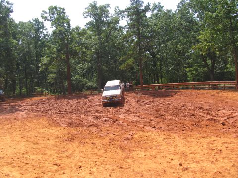 1995 Ford C-350 (Centurion Conversions) - Off-road vehicle driving through thick mud on a sunny day.