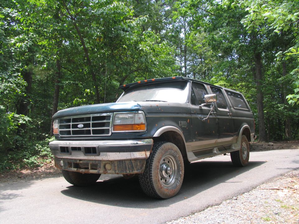 Dark green Ford Bronco Centurion with a chrome grille and aftermarket visor, parked on a paved road