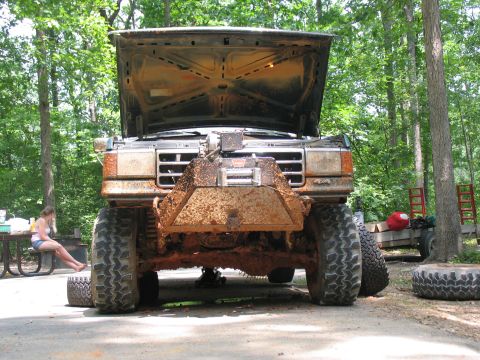 1995 Ford C-350 (Centurion Conversions) - Muddy lifted truck with hood open, parked outdoors with trees in the background.