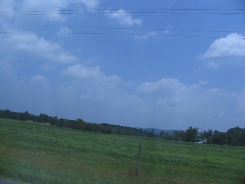1995 Ford C-350 (Centurion Conversions) - A wide view of a rural landscape with grassy hills and a distant tree line.