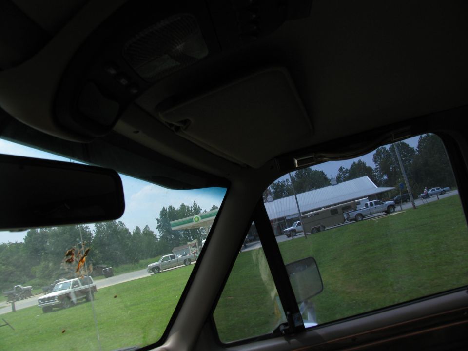 Interior view of a pickup truck with a trailer and other vehicles outside a building