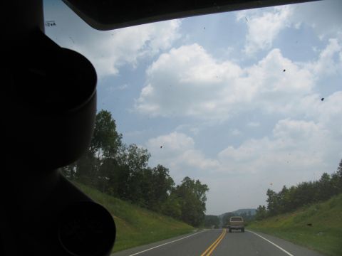 1995 Ford C-350 (Centurion Conversions) - Driving down a rural road with a truck ahead under a cloudy sky.