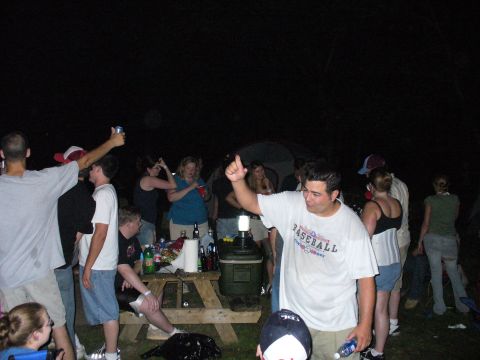 1991 Ford Probe - A group of people are socializing outdoors at night, with a picnic table and cooler visible.